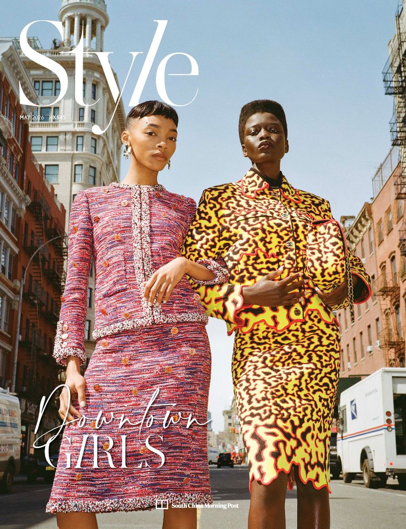 Two female models in patterned designer outfits standing on a city street under a clear blue sky