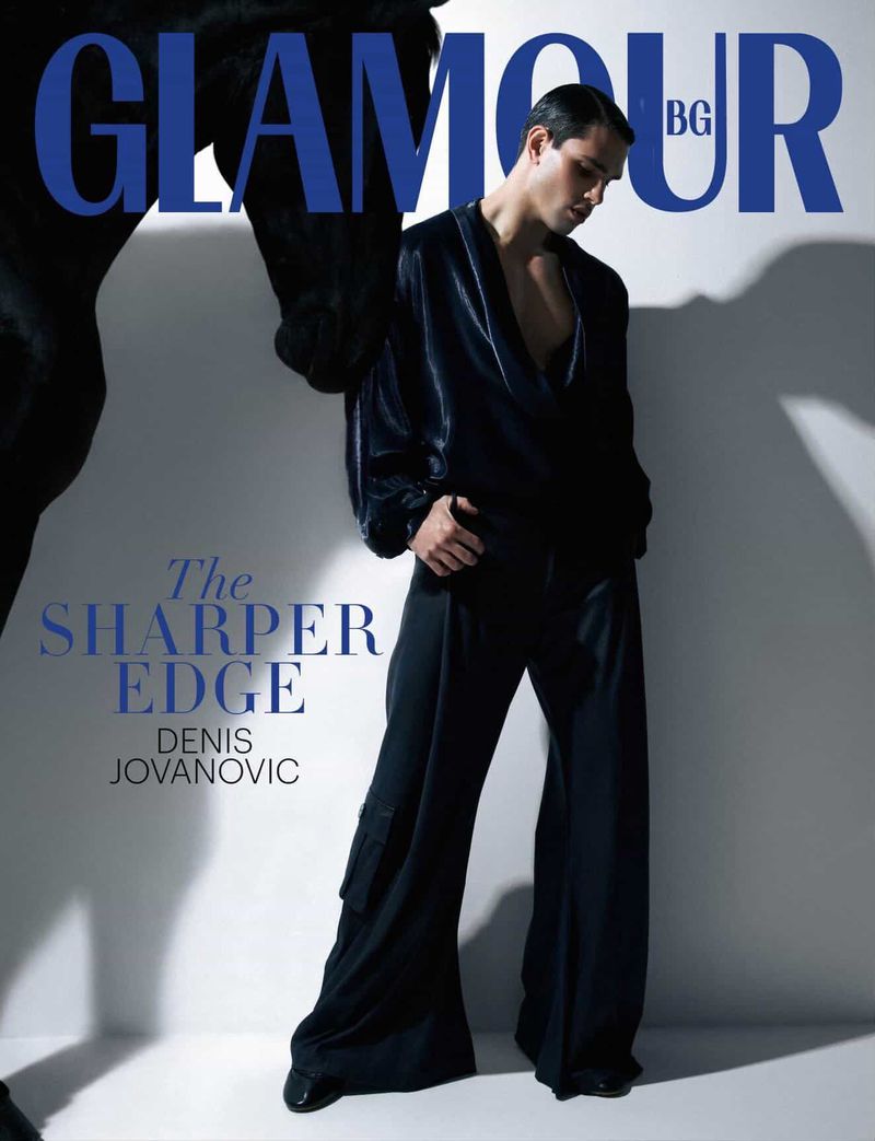 Glamour Bulgaria cover features a male fashion model in black attire, posing with part of a horse against a bright studio backdrop.