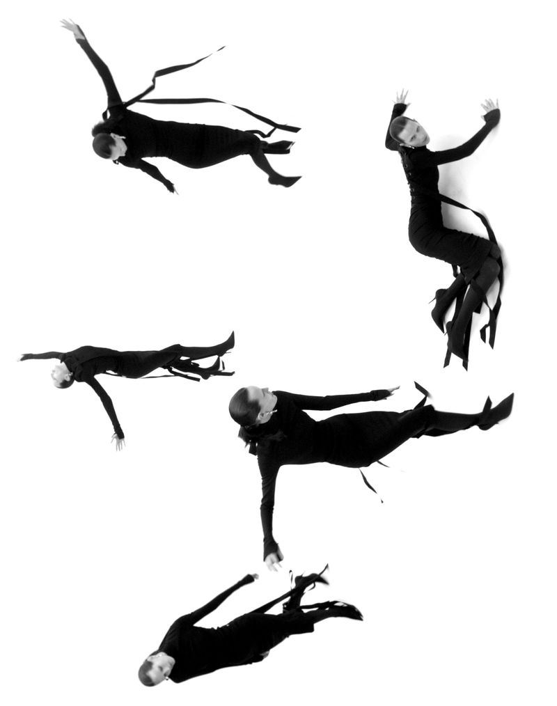Fashion shot of multiple women in long black dresses and heels posing dynamically against a stark white background in studio lighting.