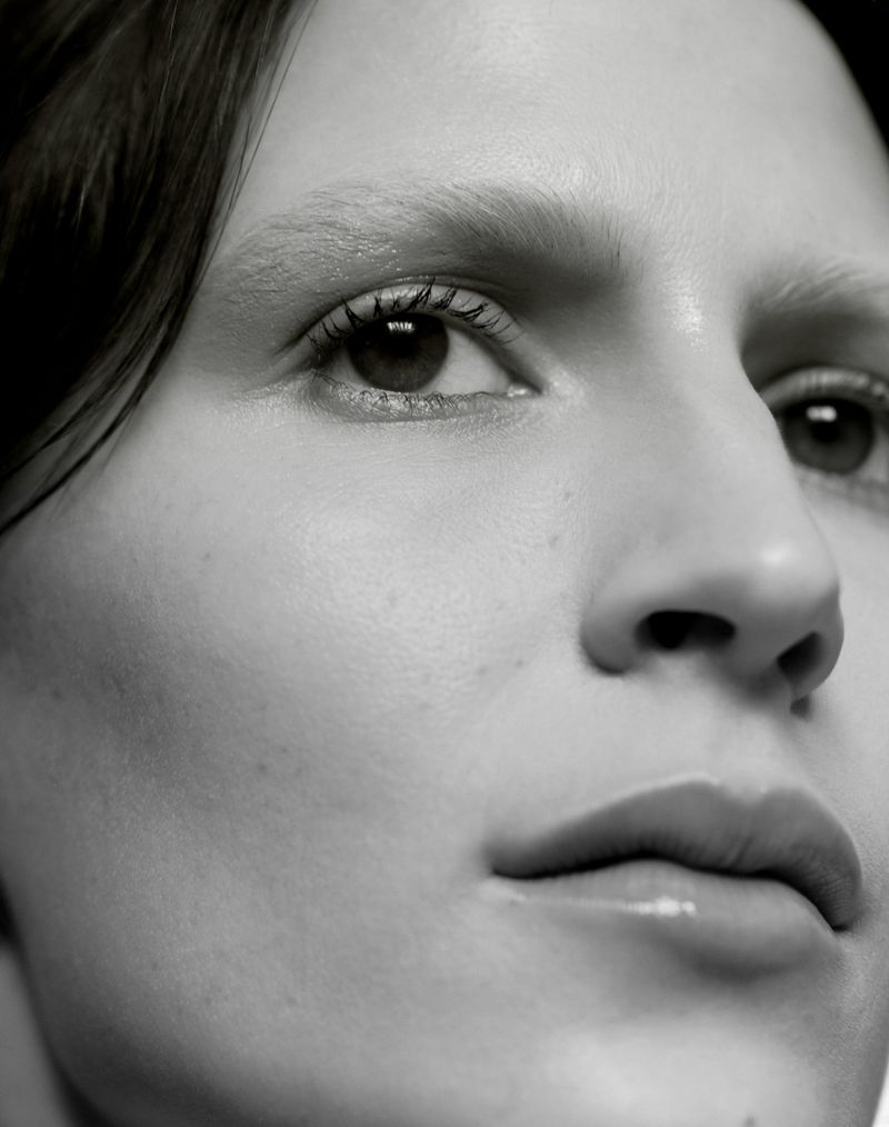 Monochrome close-up beauty portrait of model Jeanne Cadieu showing detailed skin texture, light brows, and glossy lips.