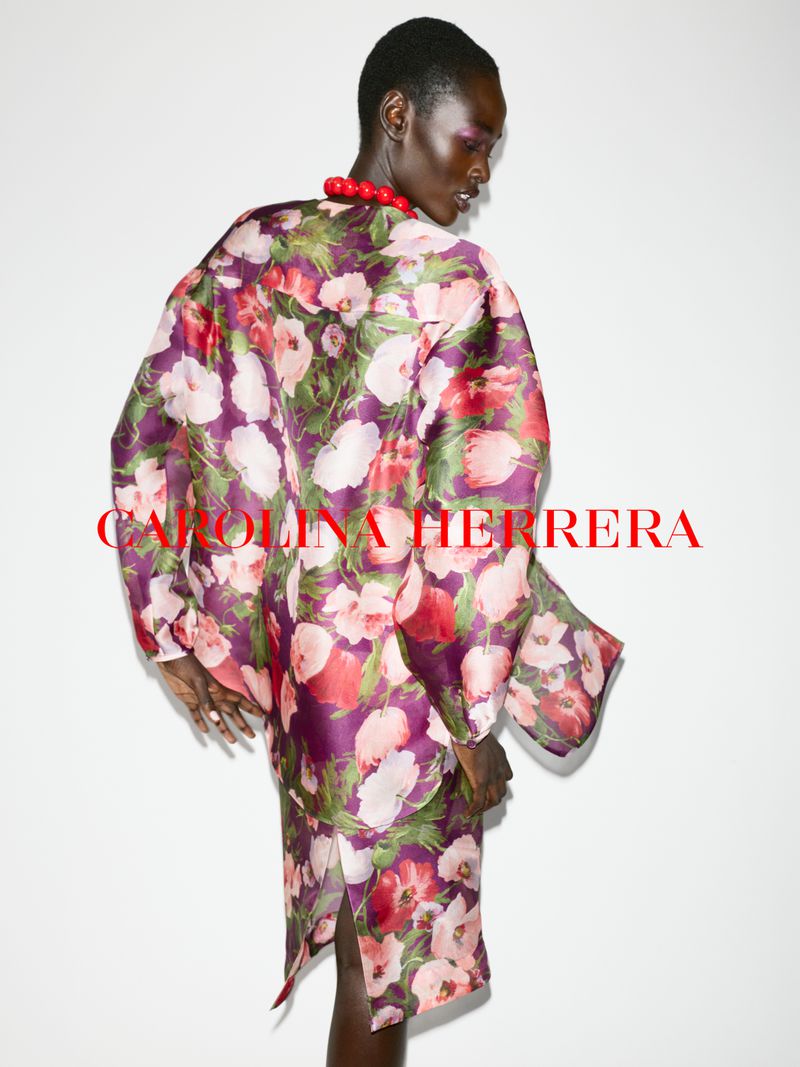 Model wearing a purple and pink floral print dress against a plain white background for Carolina Herrera