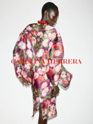 Model wearing a purple and pink floral print dress against a plain white background for Carolina Herrera