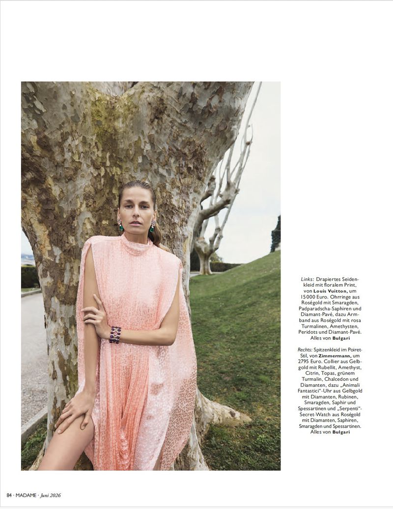 Model in a pink textured dress posing against a large tree trunk for a fashion editorial