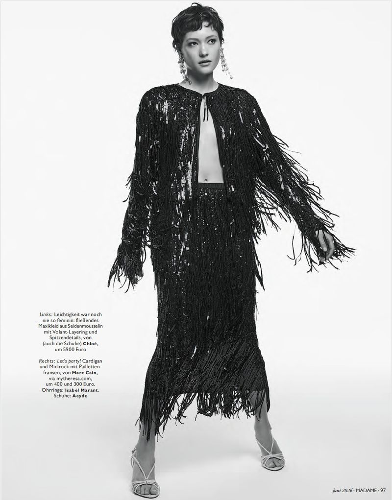 Model wearing a black sequined fringe cardigan and matching midi skirt against a plain studio background.