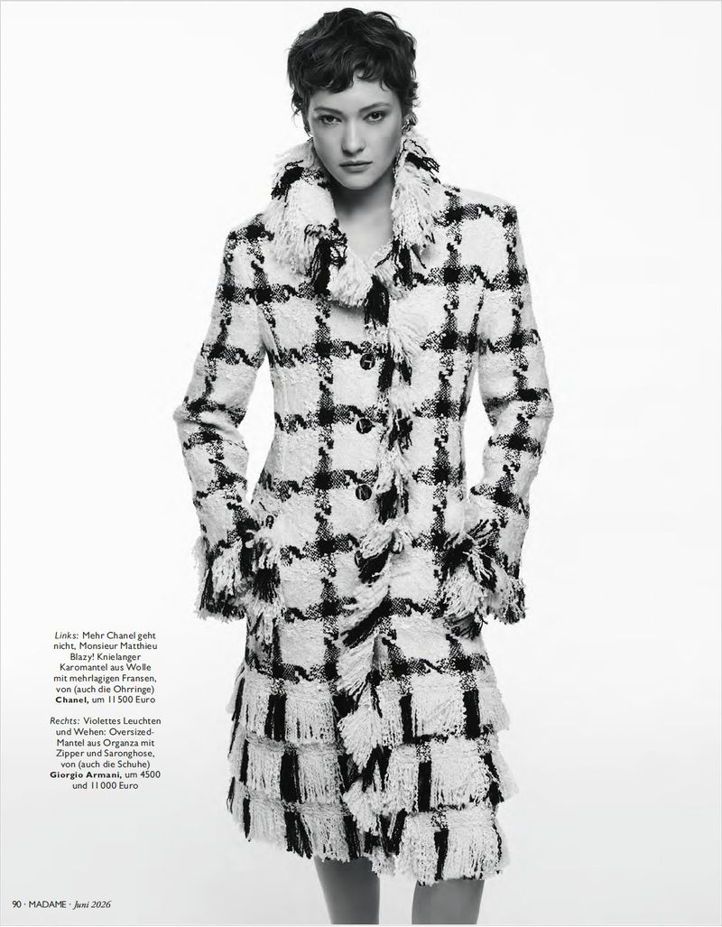 Model wearing a black and white patterned fringe coat against a white background for Madame Germany editorial