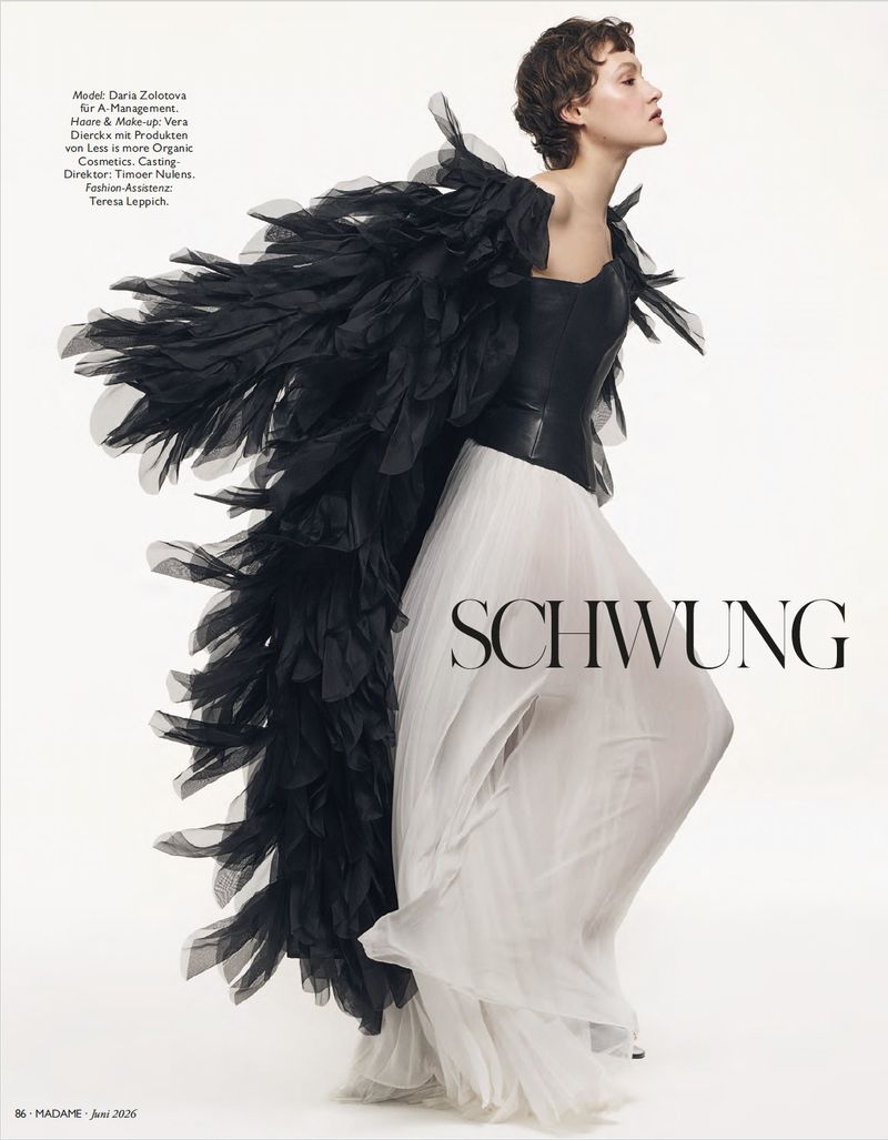Model Daria Zolotova wearing a black feathered cape and white gown against a plain white background for Madame Germany.