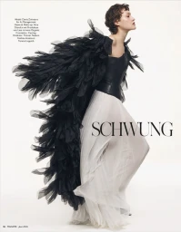 Model Daria Zolotova wearing a black feathered cape and white gown against a plain white background for Madame Germany.
