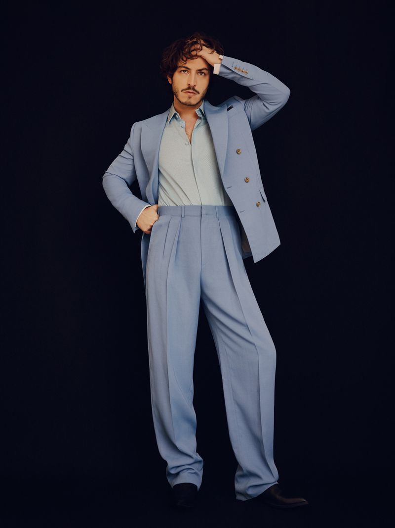 Actor Boran Kuzum wearing a light blue double-breasted suit against a dark background for Man About Town.