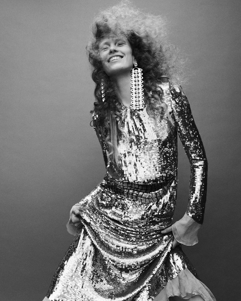 Model Leanne De Haan in a sequined dress and statement earrings smiling against a plain studio background for Numero Istanbul Persona