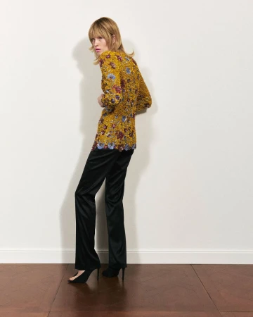Model wearing a yellow patterned top and black trousers against a neutral wall for Numéro Istanbul