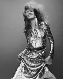 Model Leanne De Haan in a sequined dress and statement earrings smiling against a plain studio background for Numero Istanbul Persona
