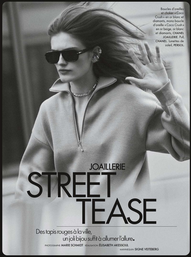 Model with sunglasses and long hair wearing a zipped collar sweater on a city street.