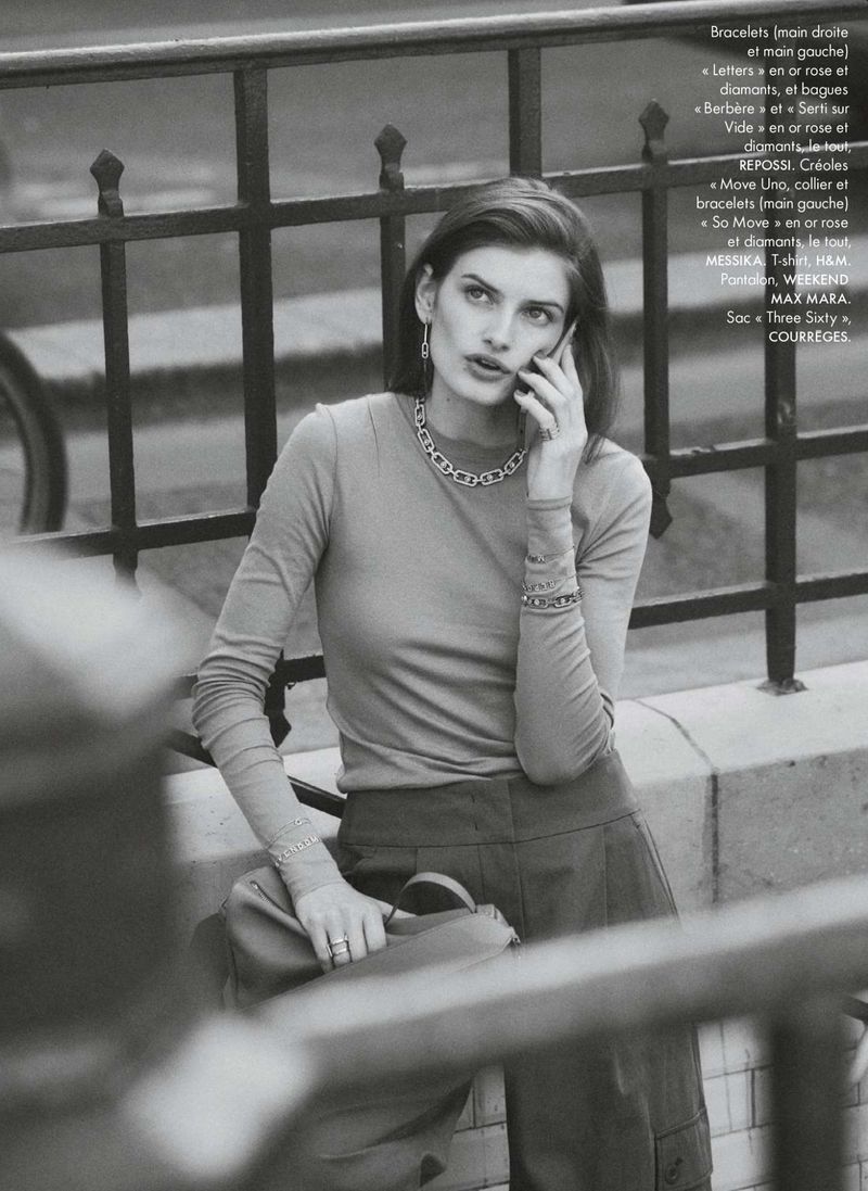 Model talking on a mobile phone outdoors leaning against a dark metal fence for Elle France