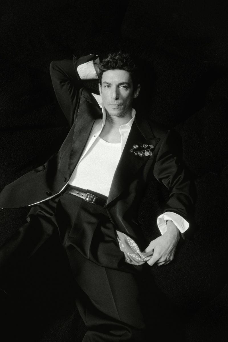 Portrait of actor Alberto Guerra in a black suit jacket and white tank top against a dark background for El Pais Icon Magazine