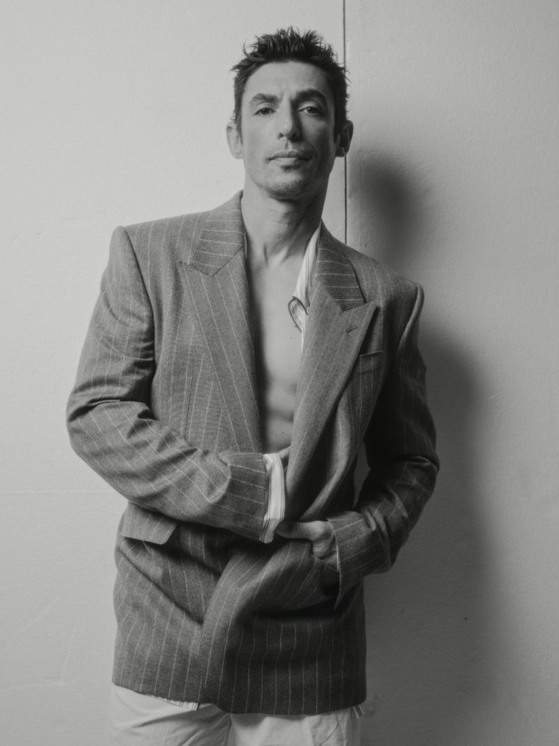 Monochrome portrait of actor Alberto Guerra wearing a pinstripe blazer against a plain white wall for El Pais Icon Magazine