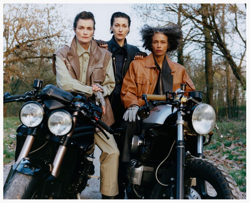 Three female models posing outdoors with two motorcycles for Family Style photographed by Estelle Hanania.