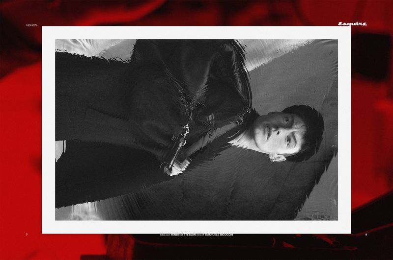 Monochrome fashion editorial featuring a young adult man in a suit jacket, presented within a framed magazine layout with bold red accents.