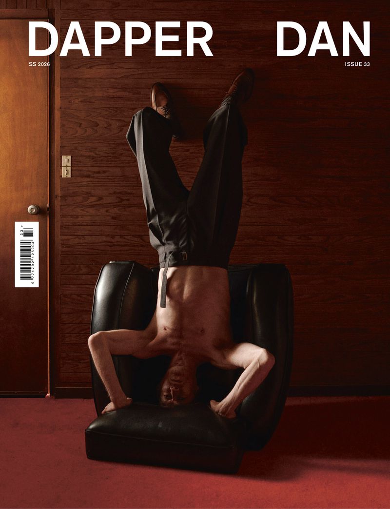Dapper Dan magazine cover featuring a shirtless adult male in black pants doing a handstand on a black leather chair indoors.