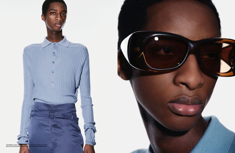 Black man wearing blue polo shirt and sunglasses against a plain white background for Dapper Dan Magazine editorial.