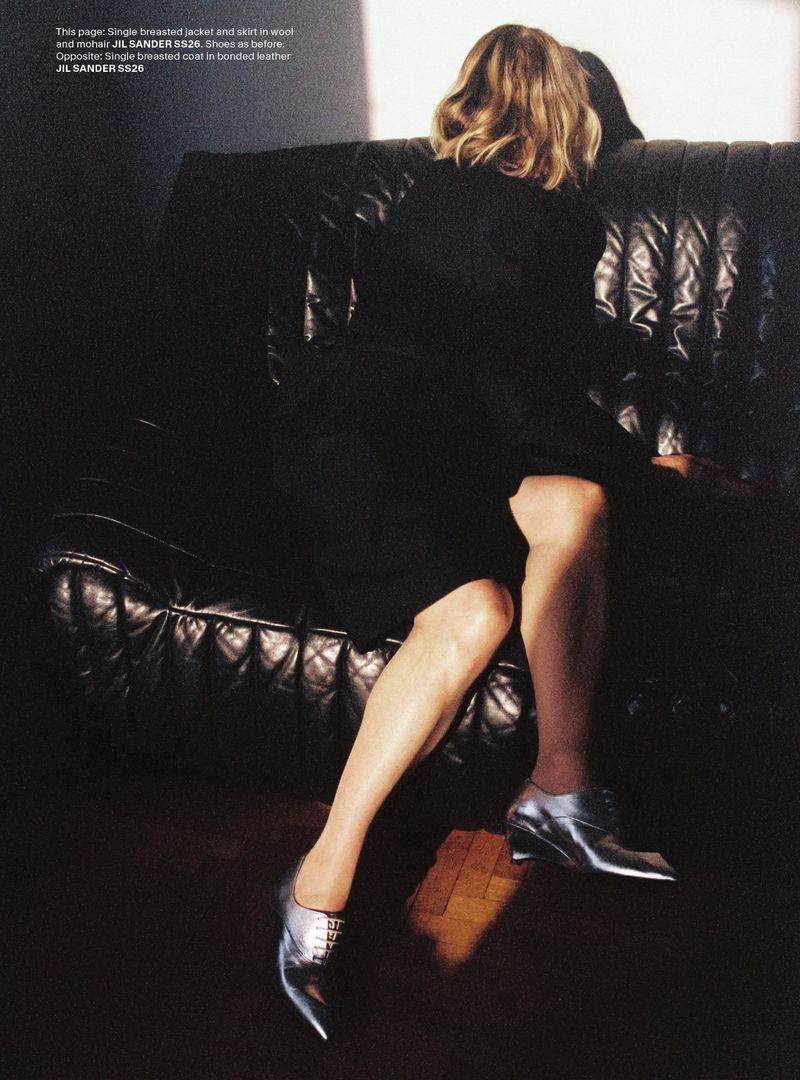 Kim Gordon wearing Jil Sander in an editorial for AnOther Man Magazine, seated on a dark leather couch.
