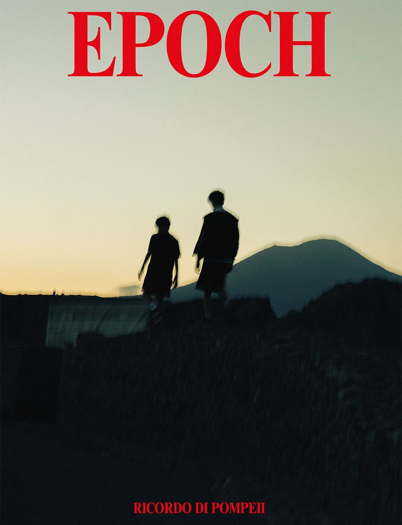 Two silhouetted figures walking against a sunset sky and distant mountain ridge under red EPOCH typography.