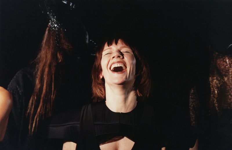 Portrait of Sandra H#00fcller laughing wearing a black dress against a dark background captured by Harley Weir