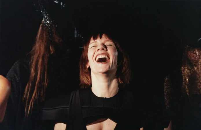 Portrait of Sandra H#00fcller laughing wearing a black dress against a dark background captured by Harley Weir