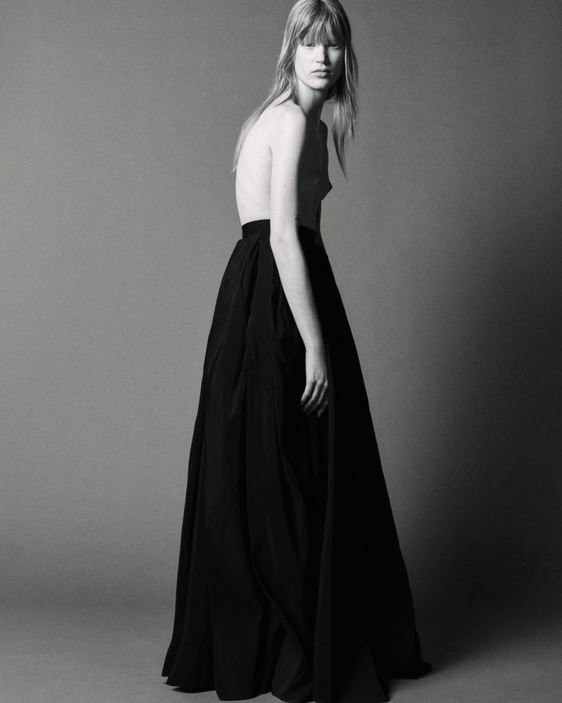 Model in a long black skirt standing against a neutral studio background for The Travel Almanac project.