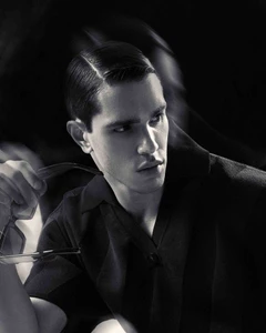 Black and white portrait of a man in a dark collared shirt holding glasses, for Glamour Man Bulgaria by Dan-Cristian Gocan.
