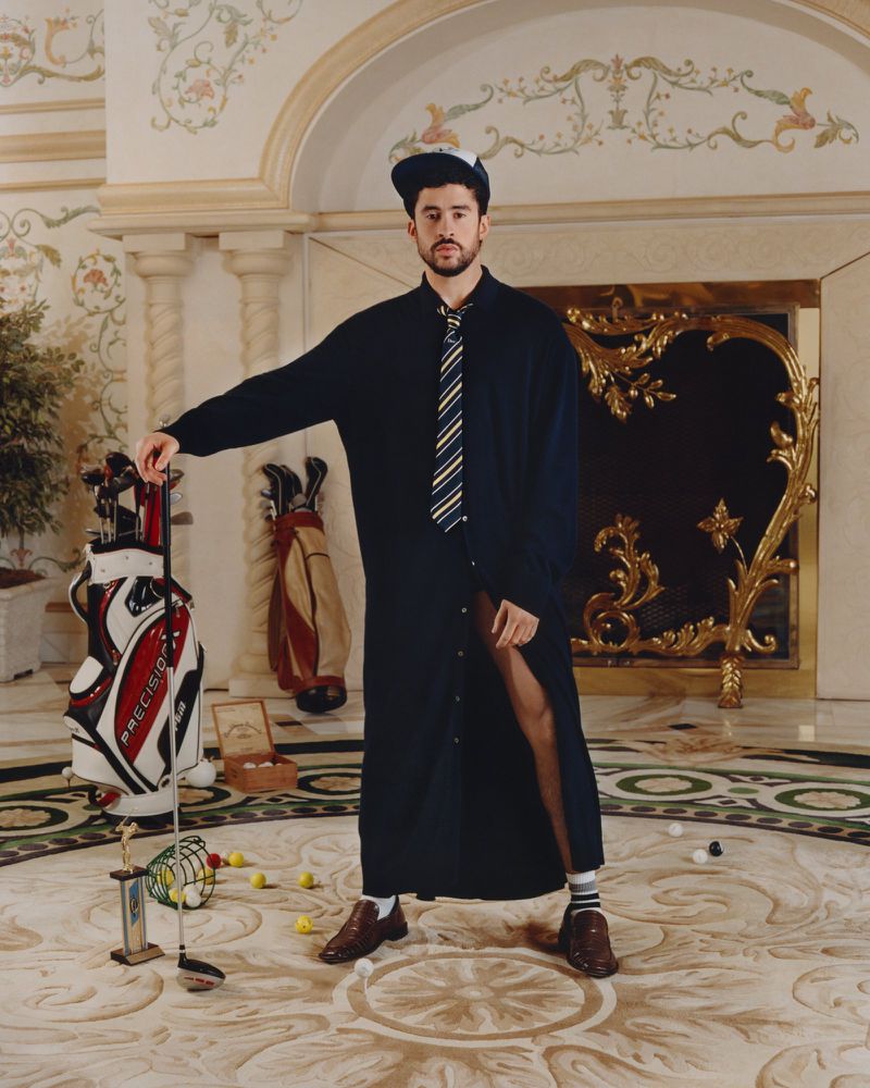 Bad Bunny posing with a golf club in a grand interior for an American Vogue editorial