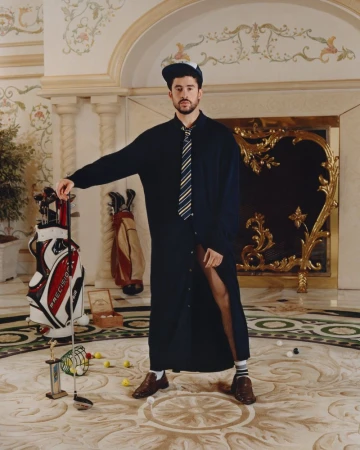 Bad Bunny posing with a golf club in a grand interior for an American Vogue editorial