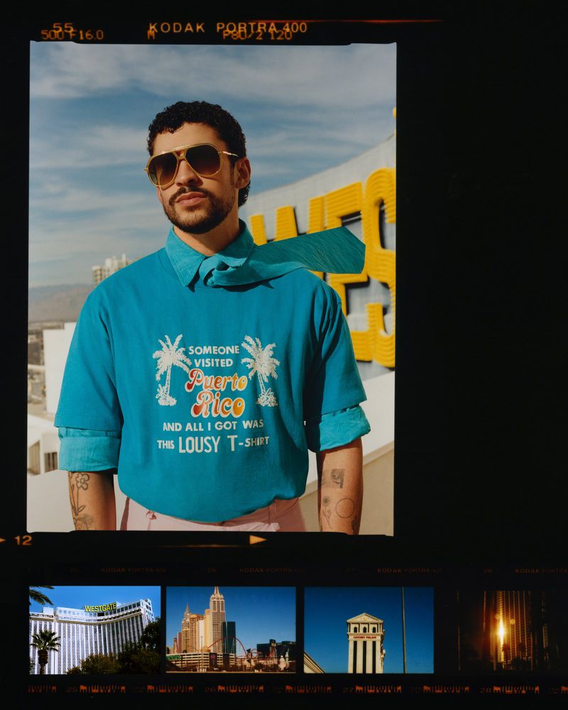 Bad Bunny wearing a blue graphic t-shirt and sunglasses against an urban rooftop backdrop with film border framing