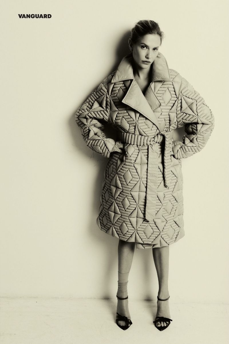 Model Veronika Baskakova wearing a quilted patterned coat against a neutral background for Vanguard Magazine