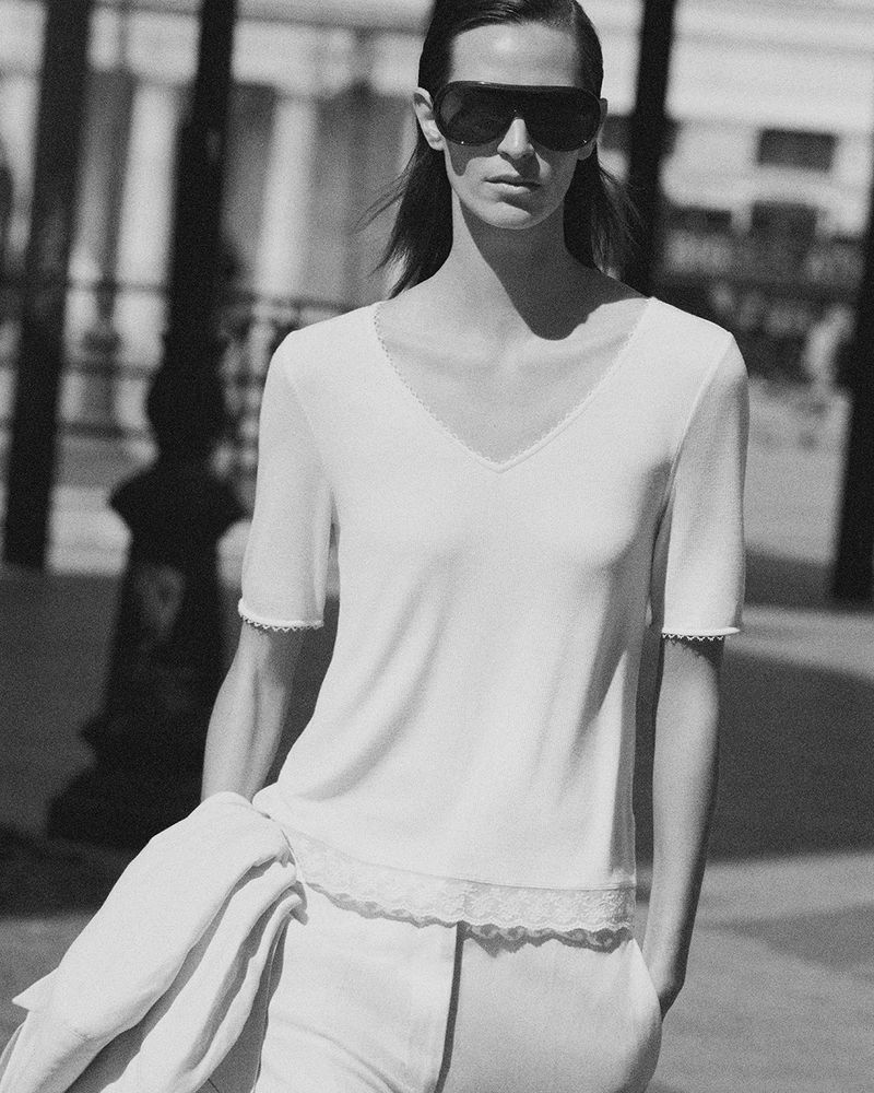 Monochrome fashion portrait of a model wearing dark sunglasses and a light V-neck top for COS Summer in the City.