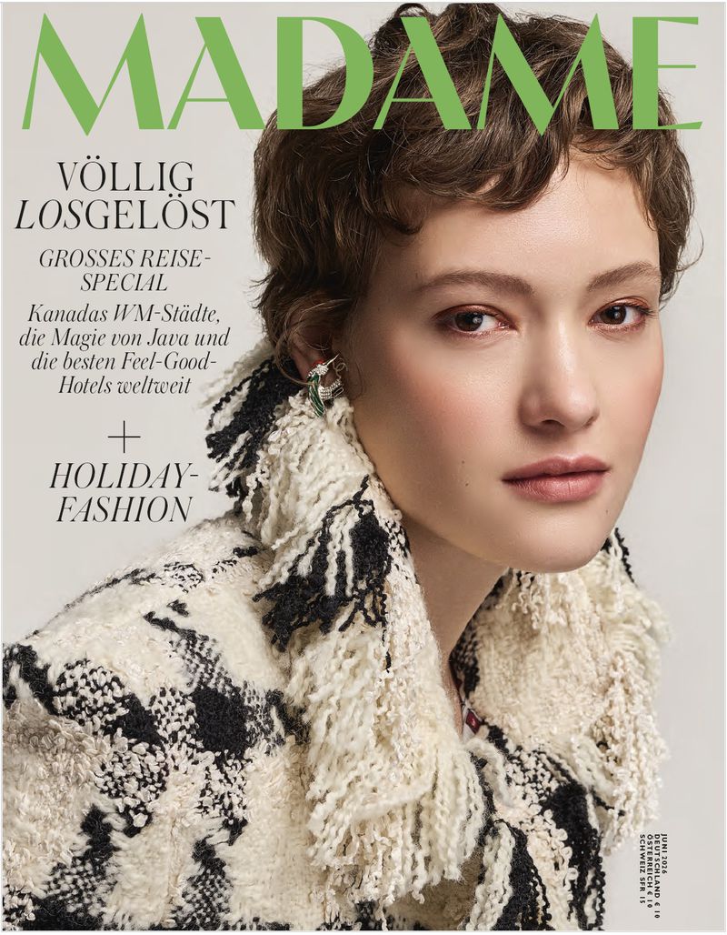 Magazine cover featuring a young woman with short curly hair wearing a patterned jacket, posing against a neutral background.