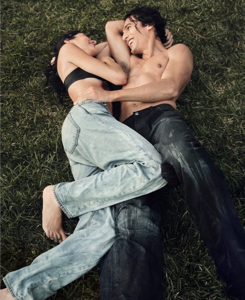 Man and woman lying together on grass wearing denim jeans for Calvin Klein photographed by Bryan Liston