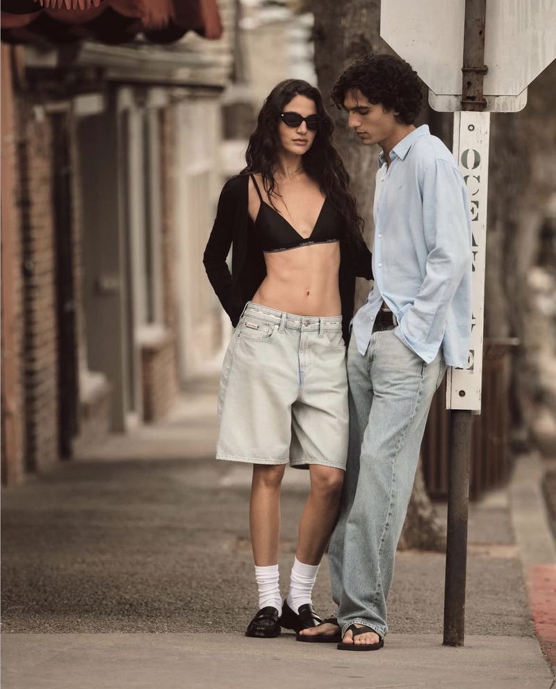 Two models standing on a city sidewalk next to a street sign for Calvin Klein campaign Less layers, better denim shot by Bryan Liston.