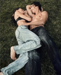Man and woman lying together on grass wearing denim jeans for Calvin Klein photographed by Bryan Liston