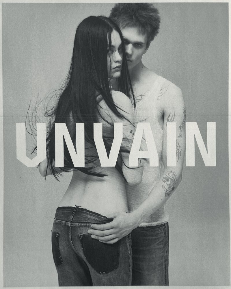 Black and white portrait of a woman and a man posing closely with large white lettering overlaying the image