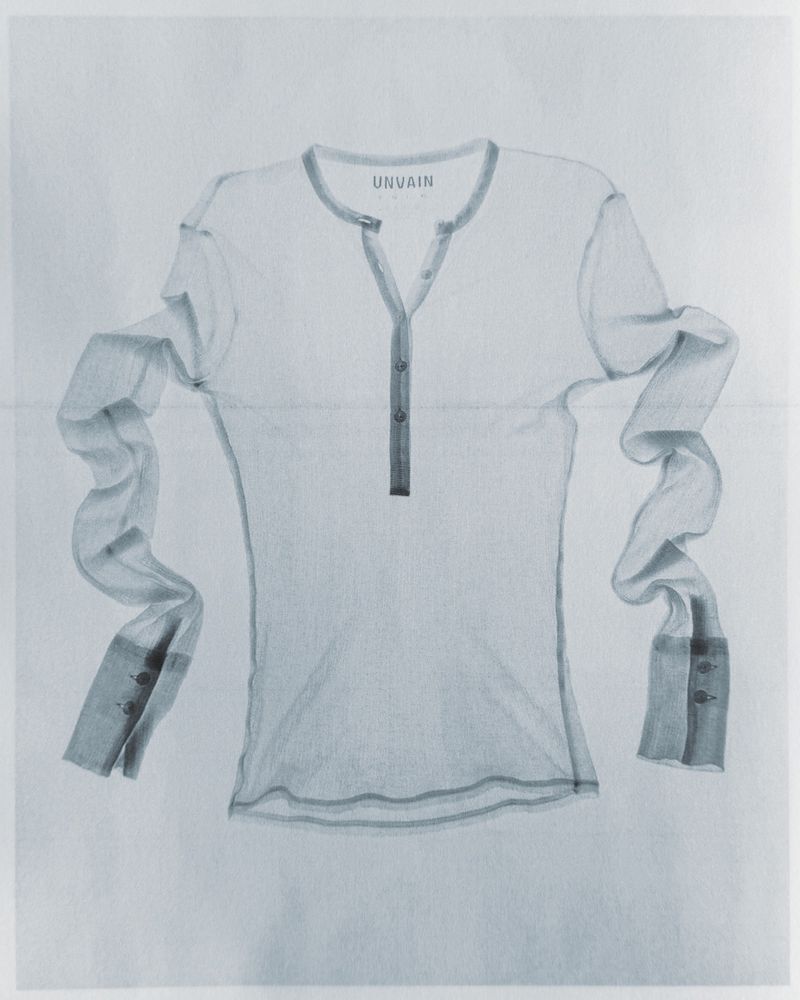 Detailed pencil or charcoal sketch of a long-sleeve henley shirt with button placket centred on a plain white paper background.