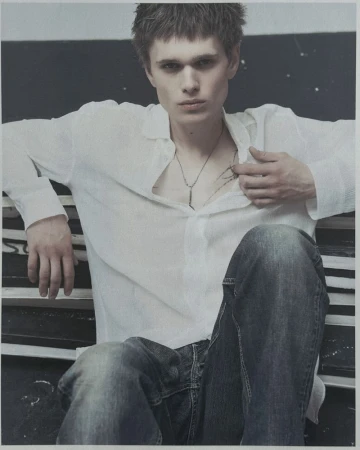 Young man wearing a white shirt and denim jeans seated indoors for Unvain Studios SS26