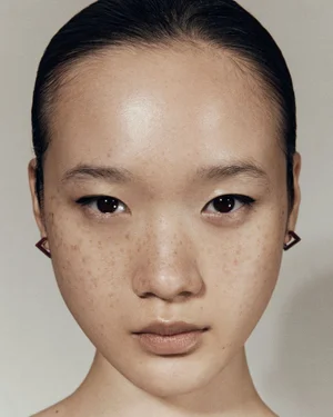 Close-up portrait of a model with freckles and geometric earrings for the Sener Besim Release 06 campaign