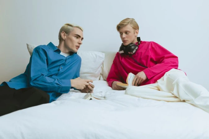 Two young male models lying on a white bed reading books for Vanity Teen Magazine editorial