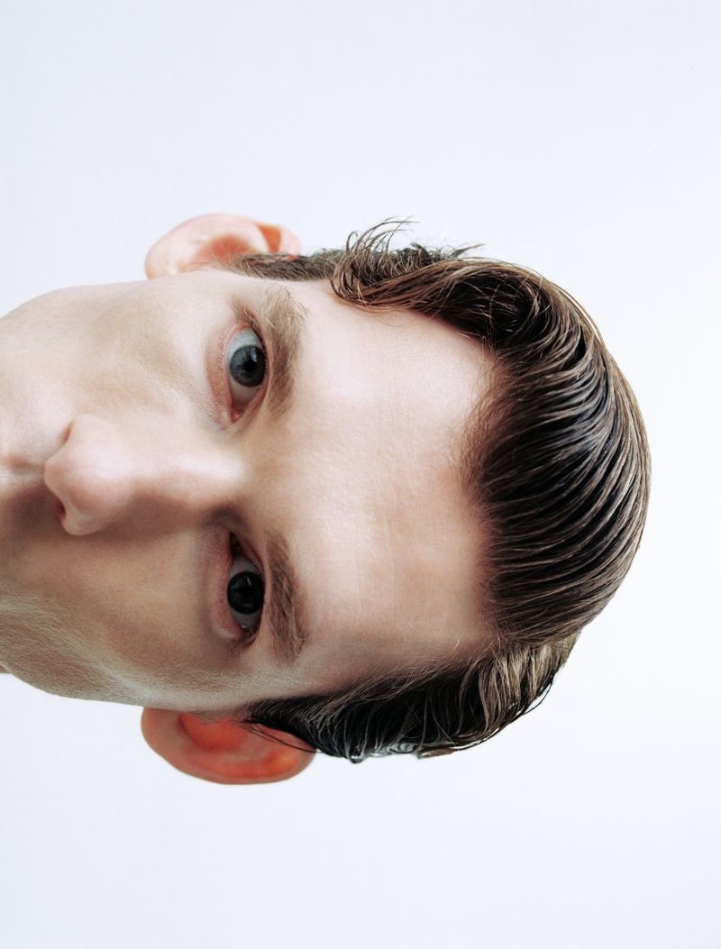 Extreme close up portrait of a man looking down against a plain white background