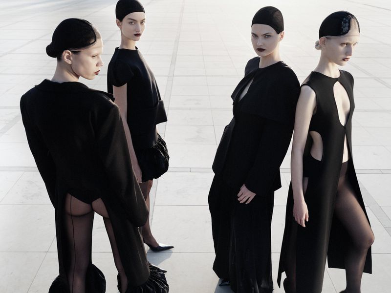 Four female models in black outfits and caps posing outdoors on a tiled plaza for Vogue Adria editorial Made in Adria.