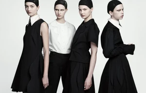 Four female models wearing black and white monochrome outfits with hair nets against a plain white seamless backdrop