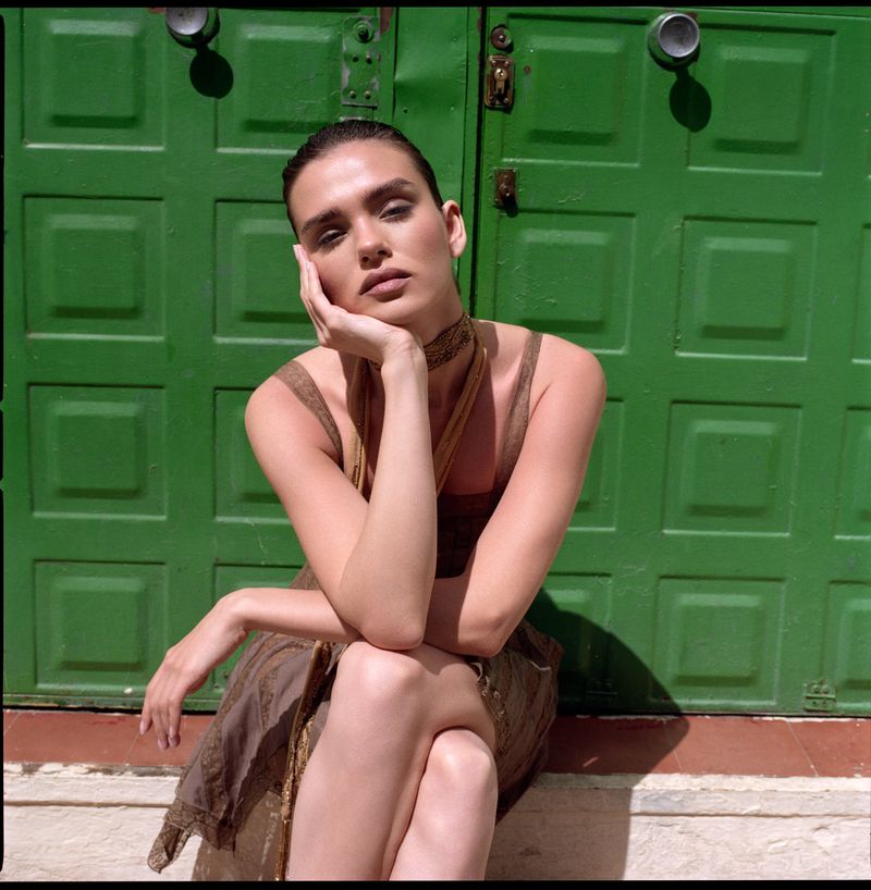 Woman resting chin in hand seated in front of a green paneled door for Vika K portrait