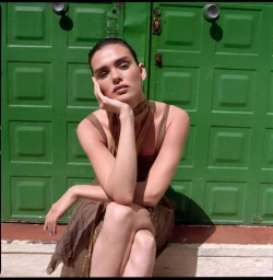 Woman resting chin in hand seated in front of a green paneled door for Vika K portrait