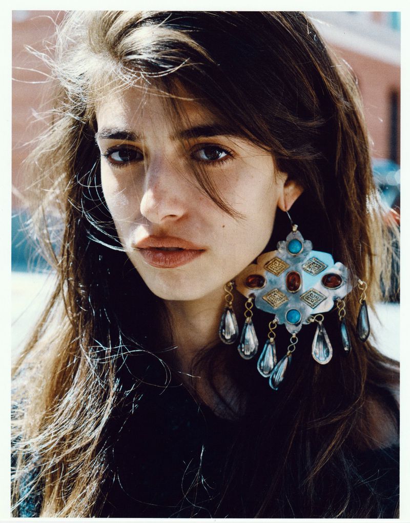 Close-up portrait of a woman with long dark hair wearing large ornate silver earrings with turquoise stones for Cala by Johnson Lui