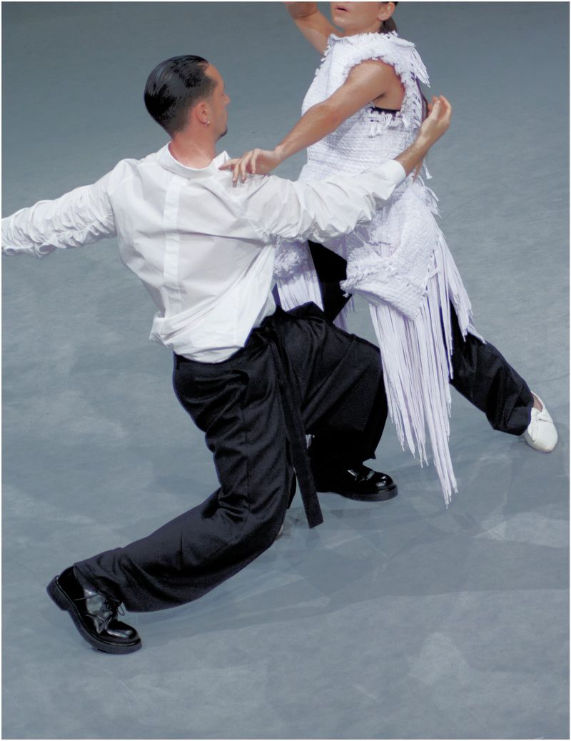 Two dancers in white shirts and dark trousers performing on a grey studio floor for Dapper Dan Magazine editorial.